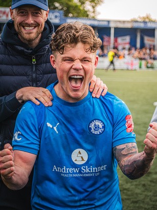 Footballer roaring in celebration with a teammate behind him