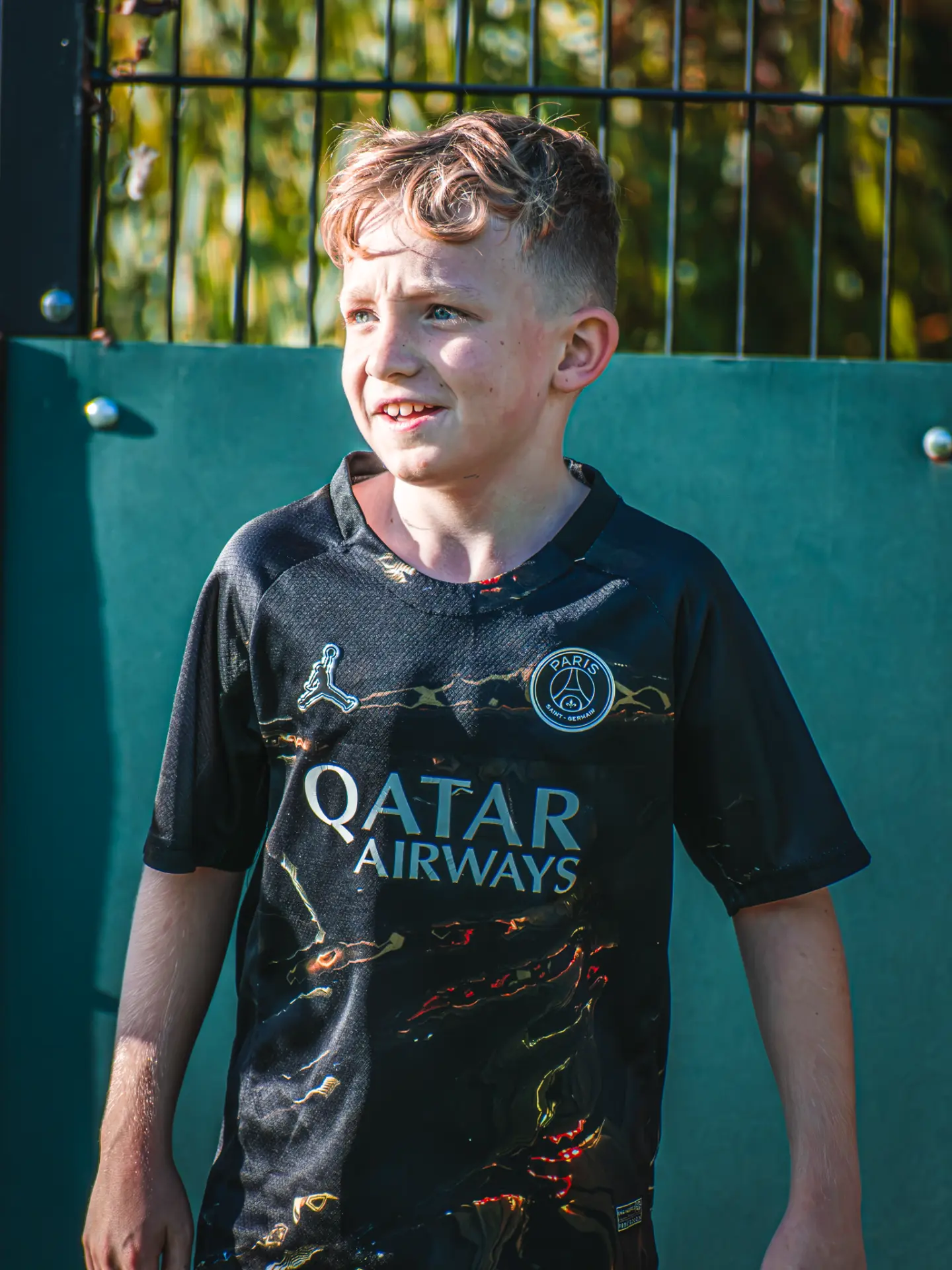 Young player smiling beside the pitch fence
