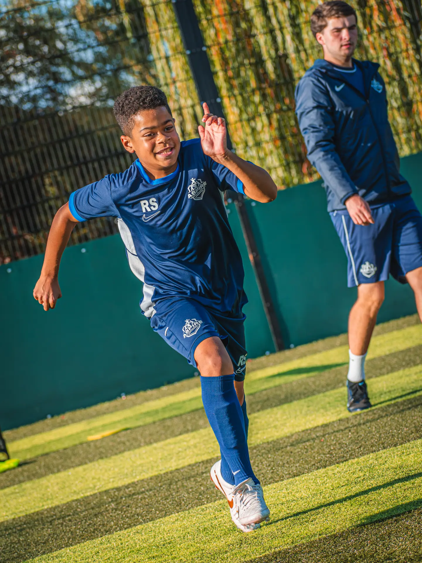 Player celebrating during a running drill with a coach behind