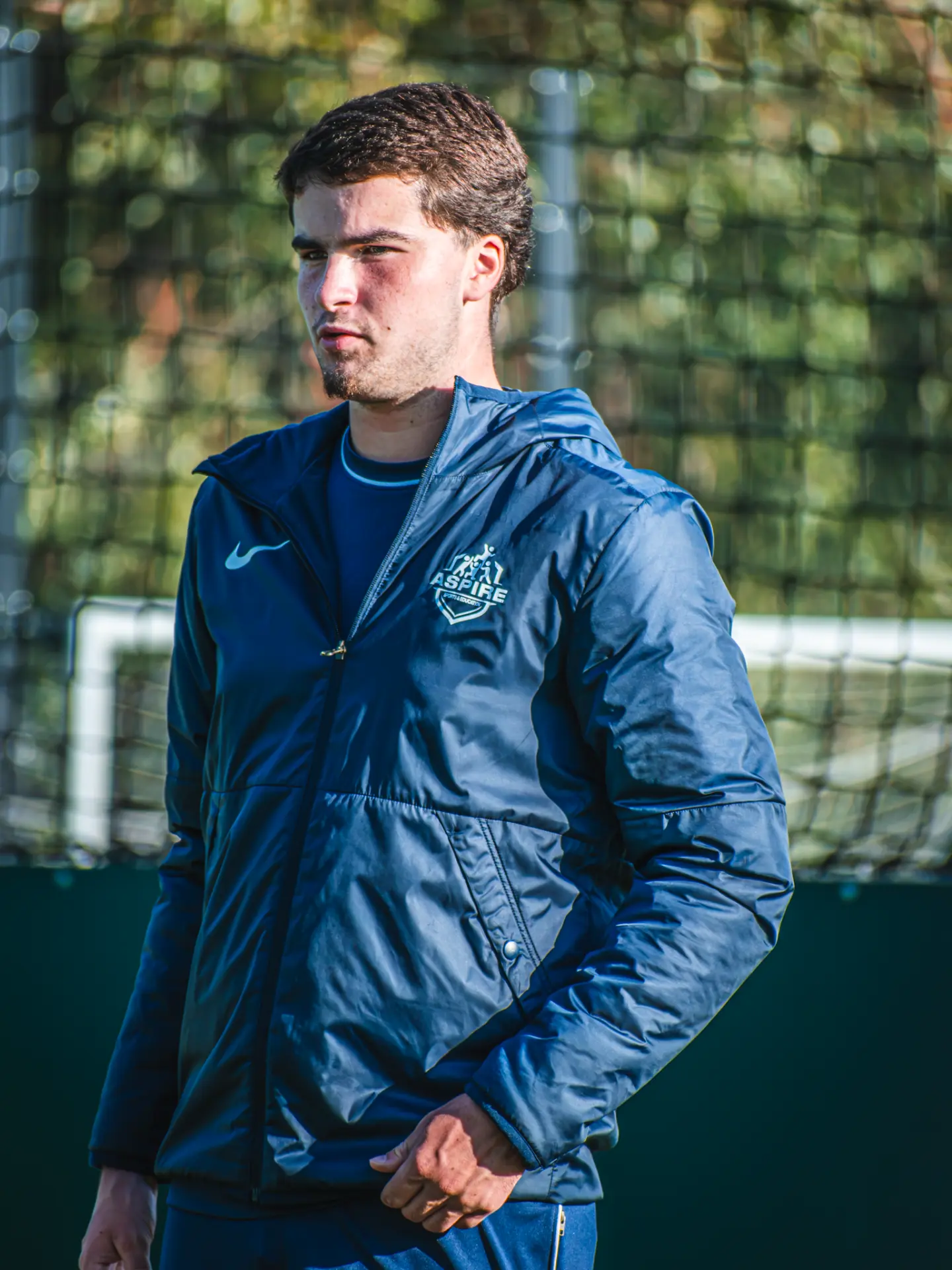 Aspire coach in a navy jacket watching the session