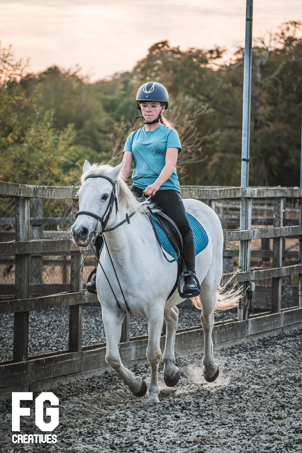White horse in motion with its rider in an outdoor arena