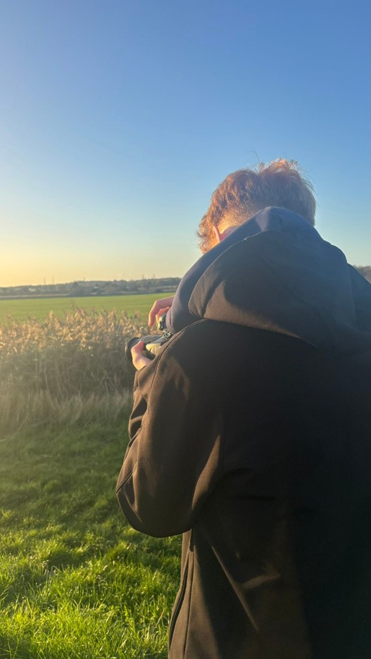 Creator shooting handheld into a golden field at sunset
