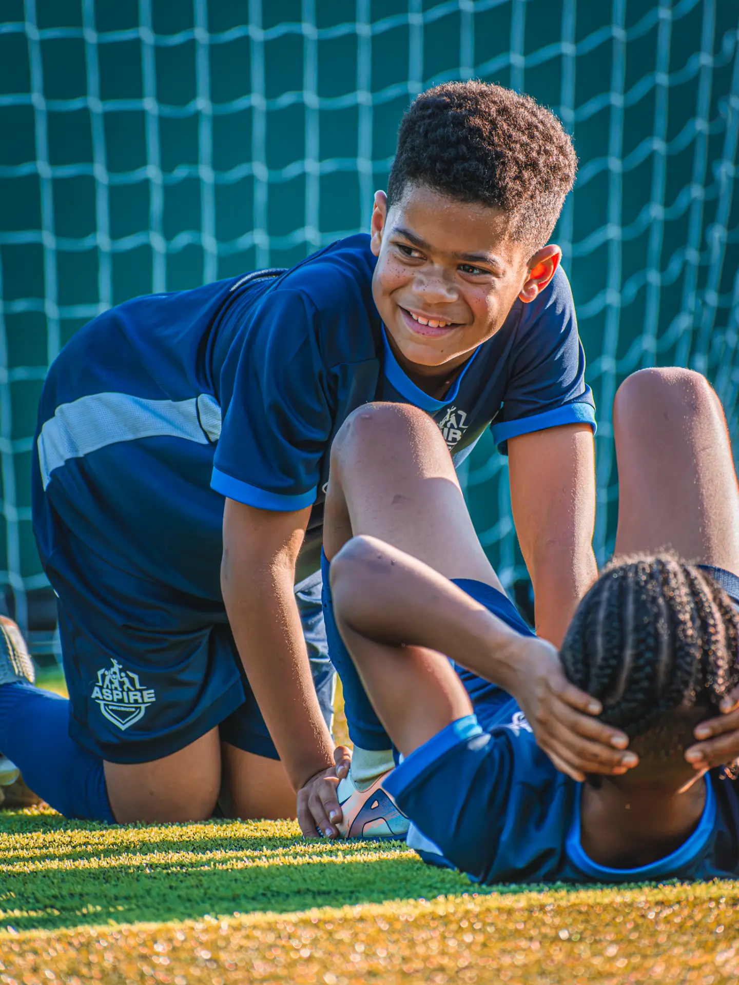 Two Aspire players laughing during a stretching exercise